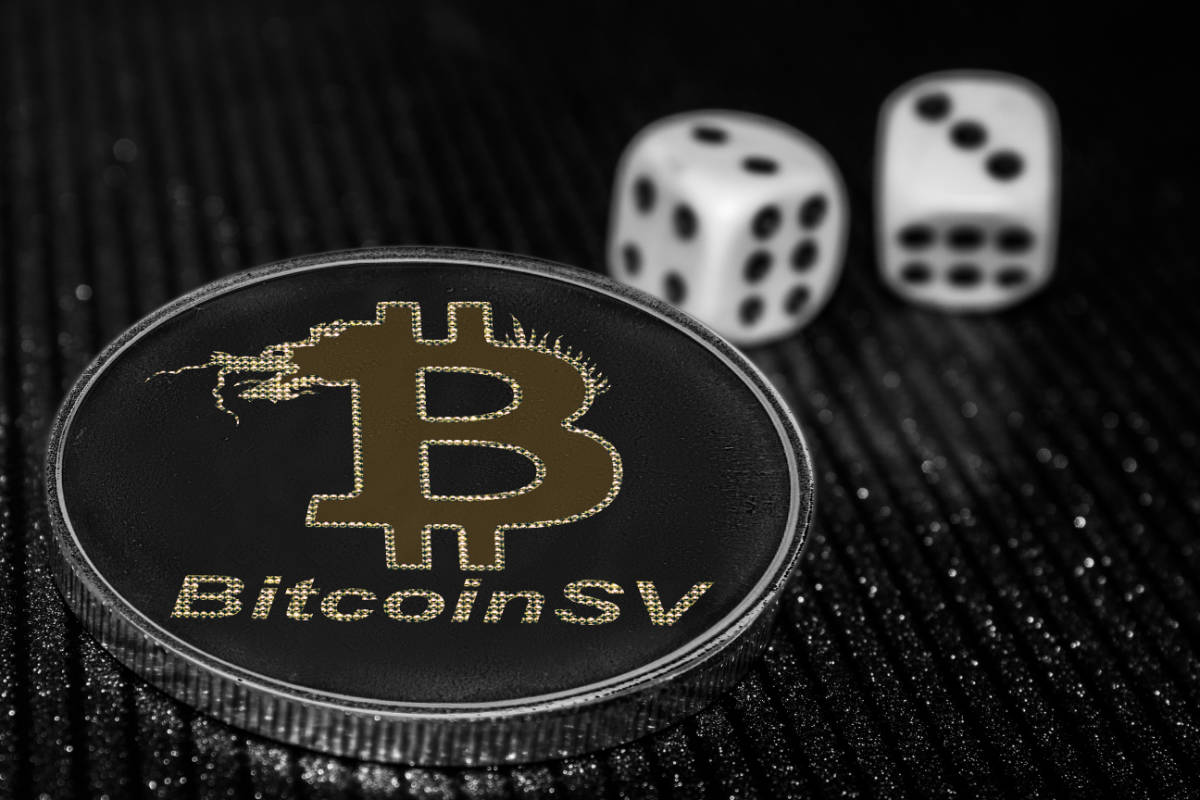 Eine Bitcoin-Münze mit 'Bitcoin SV' Schriftzug liegt neben zwei Würfeln auf einer glitzernden Oberfläche.