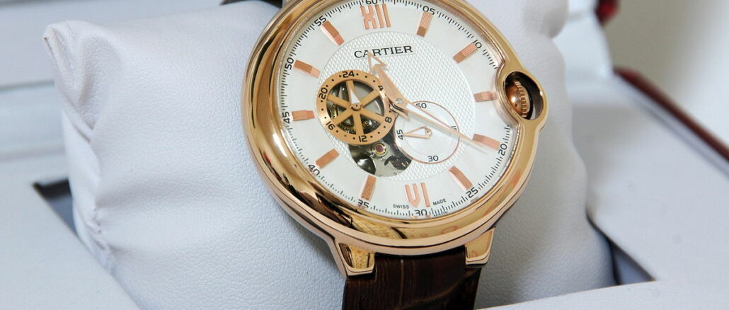 Ein Luxusuhr der Marke Cartier mit goldenem Gehäuse und Lederarmband, präsentiert auf einem weißen Kissen.