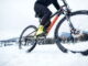 Eine Person fährt mit einem Mountainbike durch Schnee.