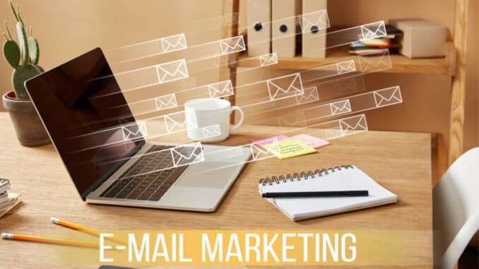 Ein Laptop auf einem Schreibtisch mit grafischen E-Mail-Symbolen, die E-Mail-Marketing darstellen.