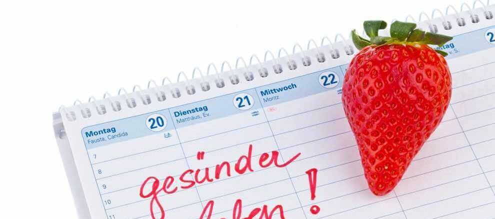 Ein Kalender mit einer Erdbeere und dem handschriftlichen Text 'gesunder leben!' auf einer Seite, die mit Montag beginnt.