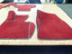 Rote Autofußmatten liegen auf einem Holztisch in einer Werkstatt zur Vorbereitung auf den Einbau.