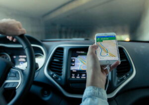 Eine Person hält ein Smartphone mit Navigationsapp im Auto.