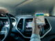 Eine Person hält ein Smartphone mit Navigationsapp im Auto.