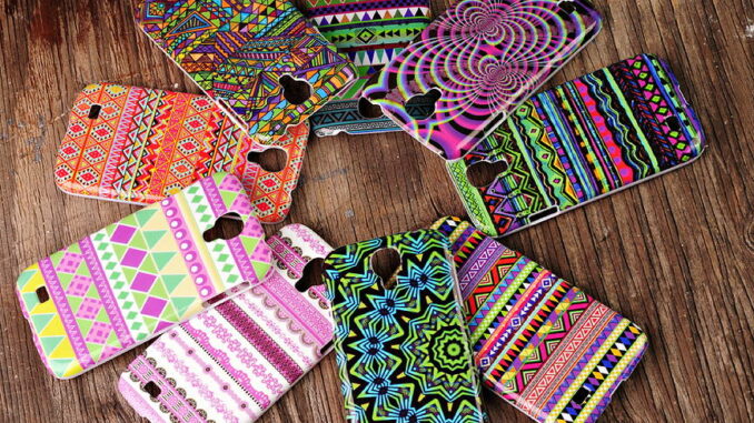 Bunte Handyhüllen mit verschiedenen Mustern liegen auf einem Holztisch.