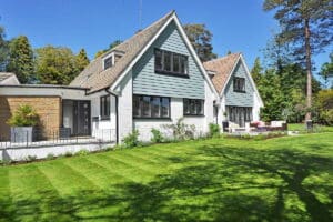 Ein helles, modernes Einfamilienhaus mit einem gepflegten grünen Garten unter klarem blauem Himmel.