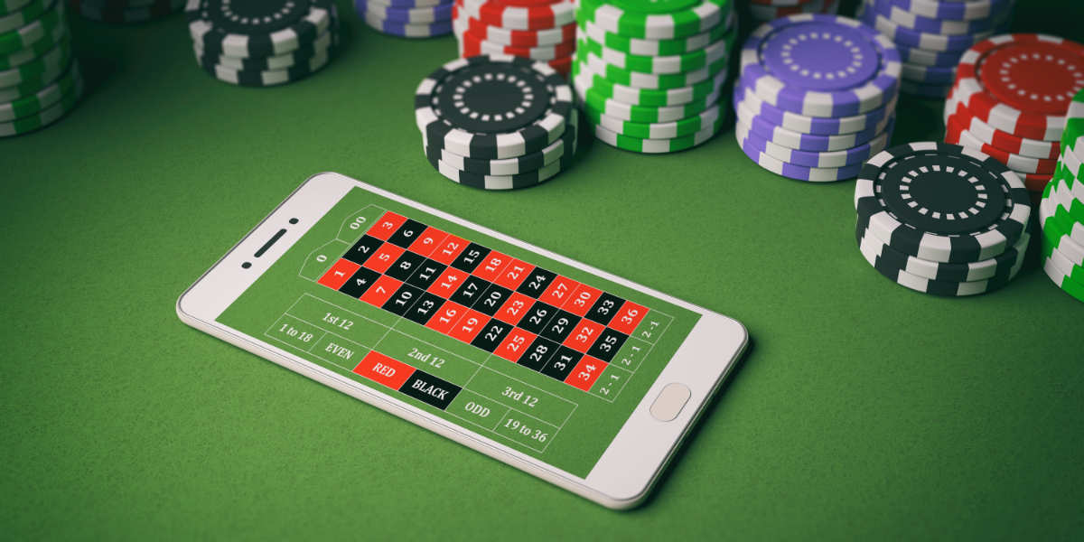 Ein Smartphone mit einer Roulette-App auf einem grünen Tisch umgeben von bunten Casino-Chips.