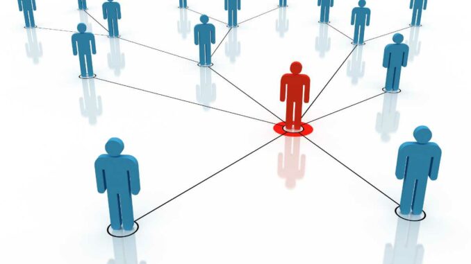 Auf dem Bild ist ein roter Mensch in der Mitte, der mit vielen blauen Menschen durch Linien verbunden ist, symbolisch für ein Netzwerk oder eine soziale Struktur.