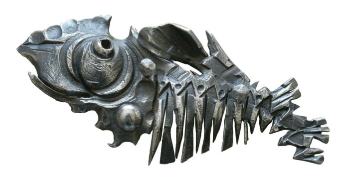 Ein metallisches Skulptur eines Fisches, hergestellt aus verschiedenen Metallteilen und Schrauben, auf weißem Hintergrund.