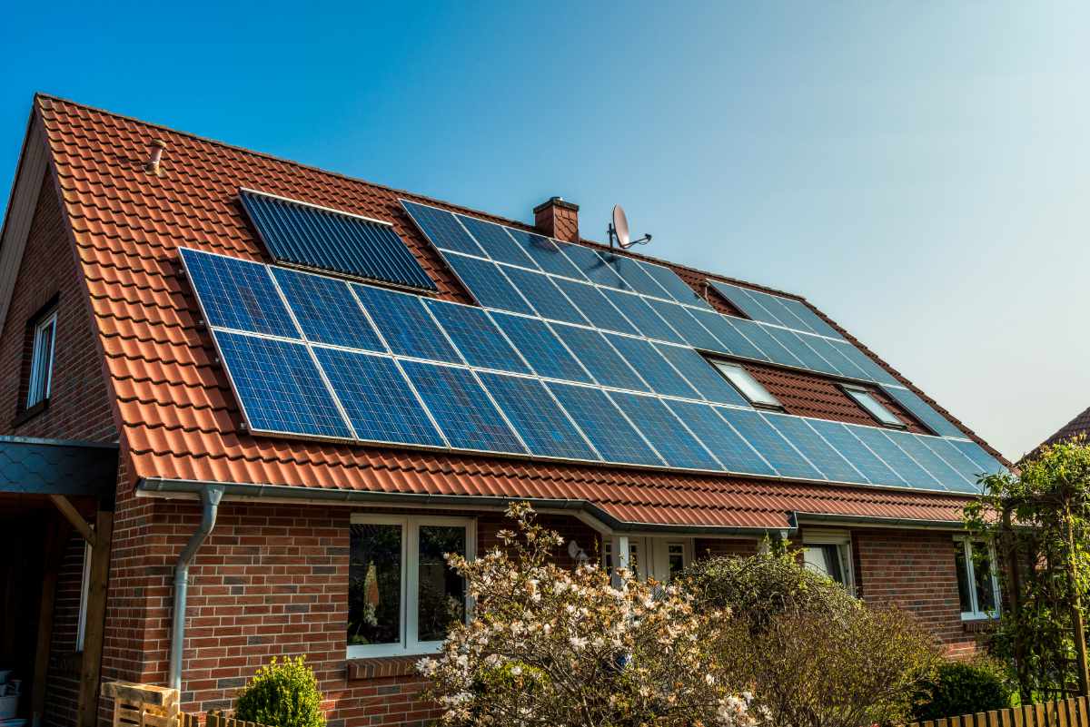 Ein Einfamilienhaus mit Ziegeldach, ausgestattet mit Solarpaneelen, unter blauem Himmel.