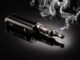 Eine E-Zigarette liegt auf dunklem Hintergrund, umgeben von Rauchschwaden.